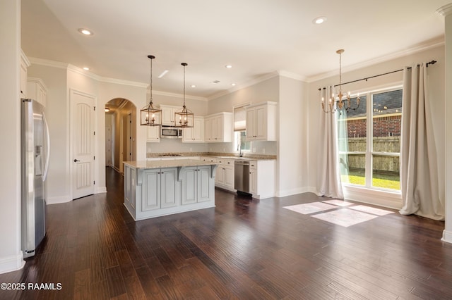 kitchen featuring arched walkways, dark wood-style floors, a center island, stainless steel appliances, and a notable chandelier