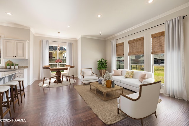 living area with dark wood-style floors, ornamental molding, a notable chandelier, and recessed lighting