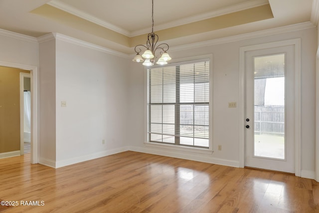 interior space with light wood-style floors, a raised ceiling, crown molding, and baseboards