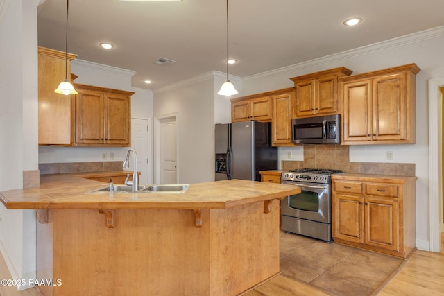 kitchen with appliances with stainless steel finishes, a peninsula, a sink, a kitchen bar, and backsplash