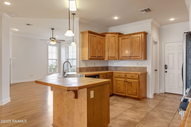 kitchen featuring crown molding, tile countertops, a sink, a peninsula, and a kitchen bar