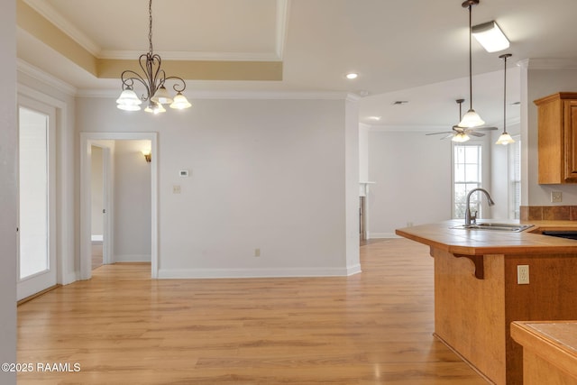 kitchen featuring light wood-style flooring, a breakfast bar area, a sink, and ornamental molding