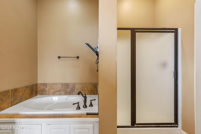 bathroom featuring a shower stall and a bath