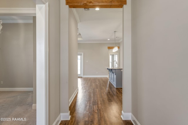 hall with visible vents, a sink, dark wood-style floors, crown molding, and baseboards