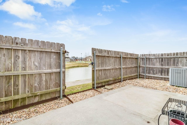 view of patio featuring central AC, a water view, and fence