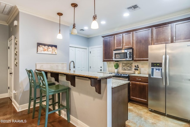 kitchen with stainless steel appliances, a breakfast bar, backsplash, and visible vents