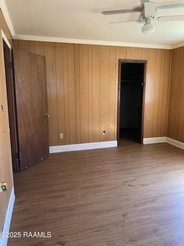 spare room featuring ornamental molding, wood finished floors, a ceiling fan, and baseboards