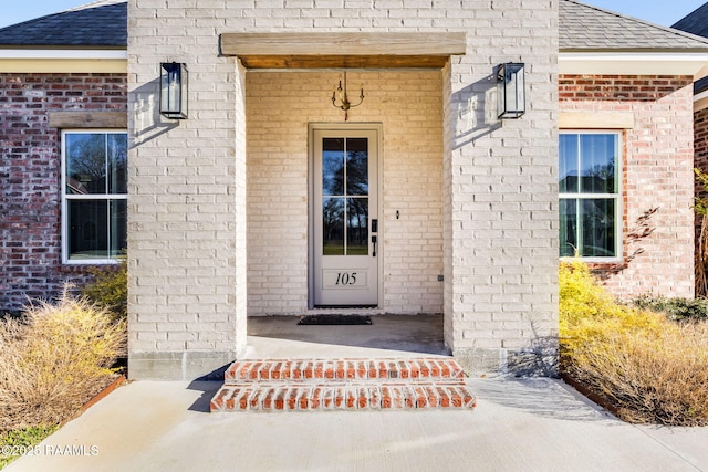 entrance to property featuring roof with shingles