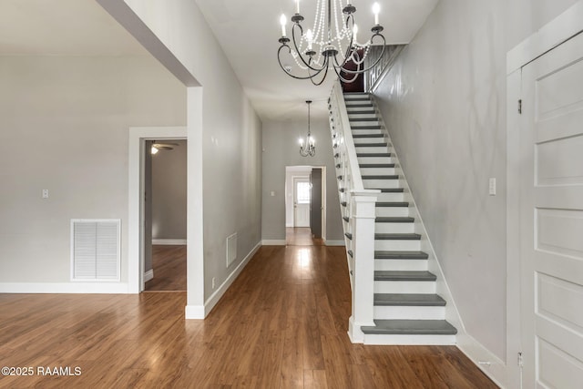 entrance foyer with an inviting chandelier, stairway, wood finished floors, and visible vents