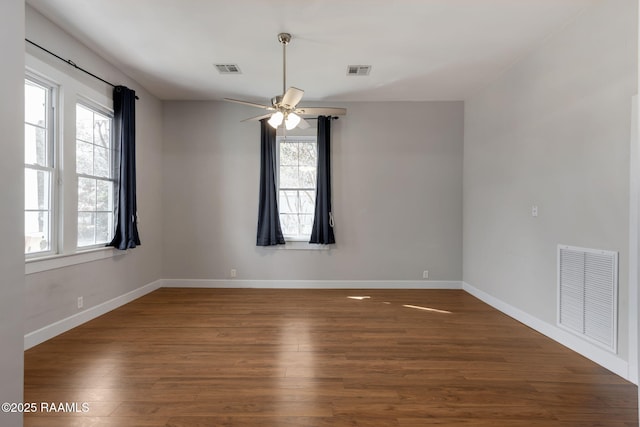 spare room with visible vents, baseboards, and wood finished floors