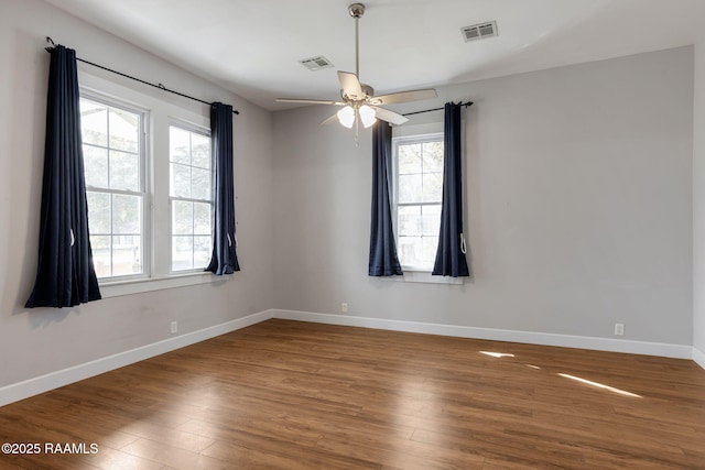 unfurnished room featuring visible vents, a ceiling fan, baseboards, and wood finished floors