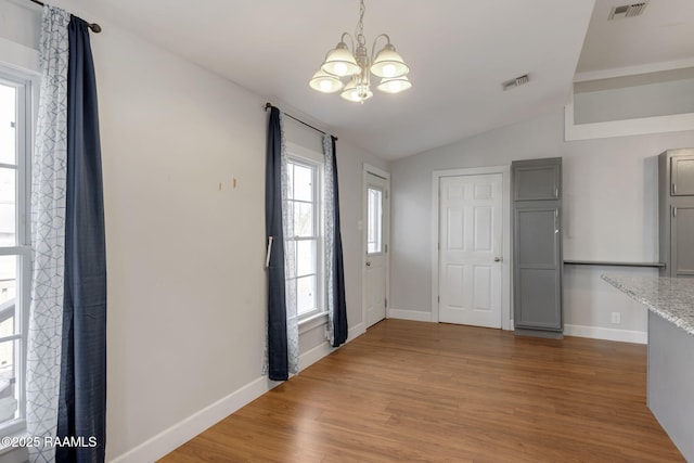 entryway with visible vents, a notable chandelier, wood finished floors, and vaulted ceiling