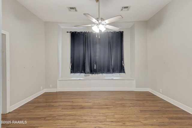 spare room with visible vents, baseboards, and wood finished floors