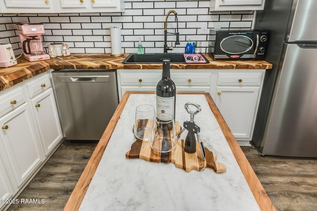 kitchen with white cabinets, dark wood finished floors, wood counters, stainless steel appliances, and a sink