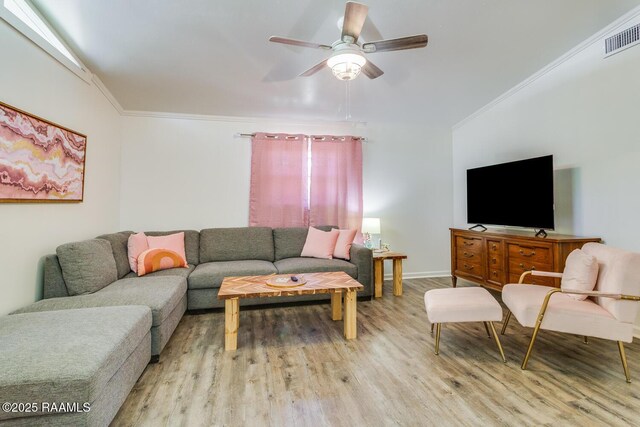 living room featuring a ceiling fan, visible vents, crown molding, and light wood-style flooring