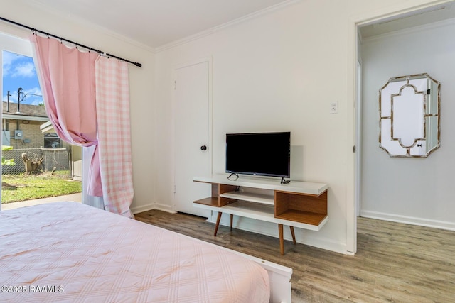 bedroom with crown molding, baseboards, and wood finished floors