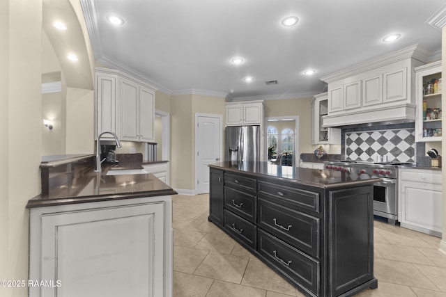 kitchen featuring dark countertops, a kitchen island, appliances with stainless steel finishes, dark cabinets, and a sink