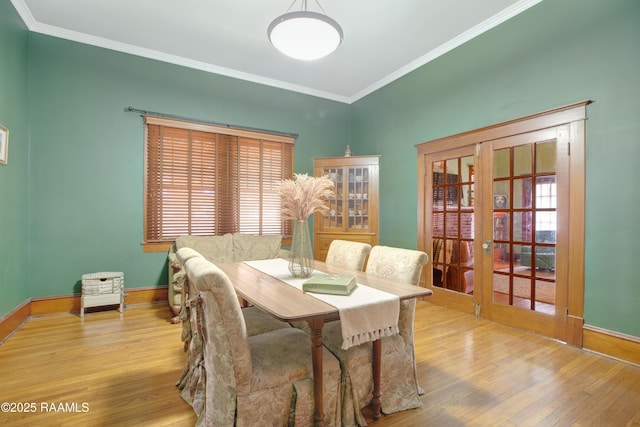 dining space featuring ornamental molding, light wood-type flooring, french doors, and baseboards