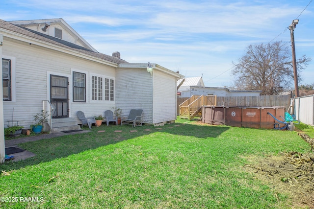 back of property with a yard, fence, and a fenced in pool