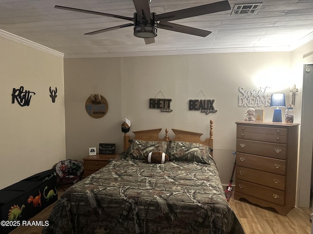 bedroom featuring a ceiling fan, visible vents, crown molding, and wood finished floors