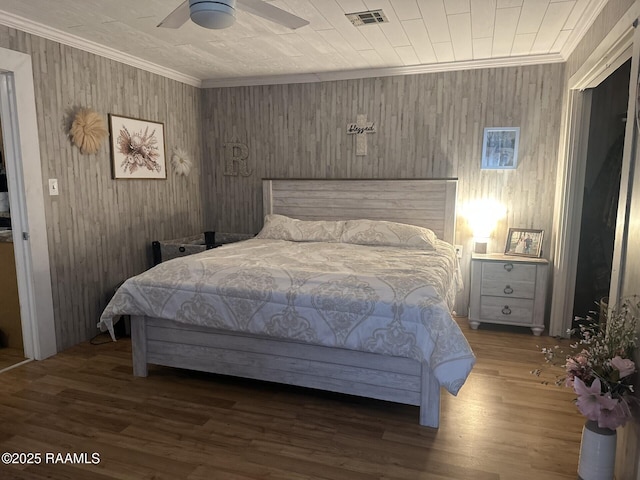 bedroom with ornamental molding, wood finished floors, visible vents, and a ceiling fan