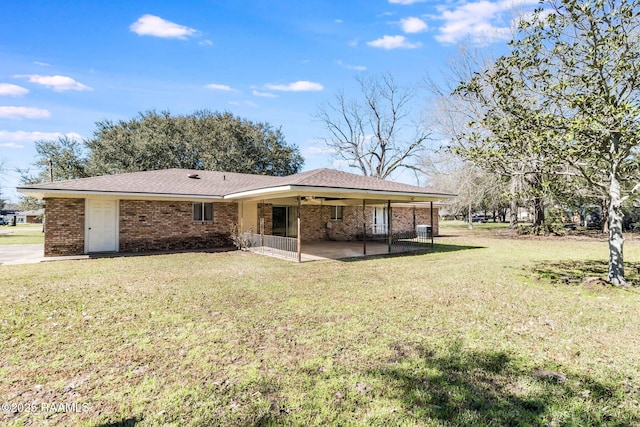 back of property featuring a yard, a patio, and brick siding