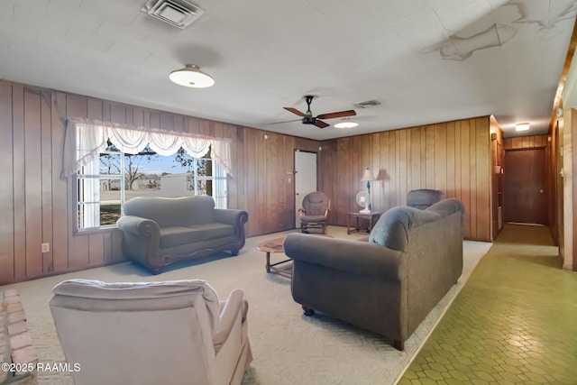 living area featuring visible vents, ceiling fan, and wooden walls