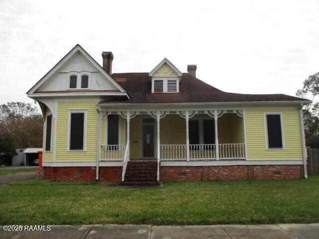 312 N State St, Abbeville, LA 70510 - view of front of home featuring crawl space, covered porch, and a front lawn