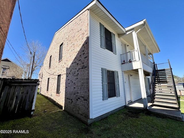 view of side of property with stairs, a yard, brick siding, and fence