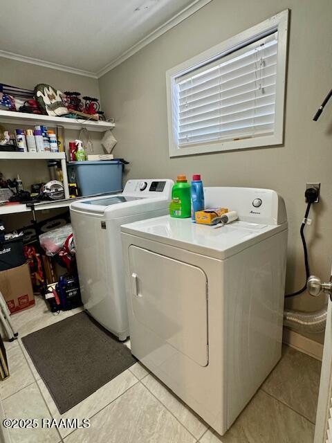 laundry area with laundry area, washing machine and dryer, light tile patterned floors, and crown molding