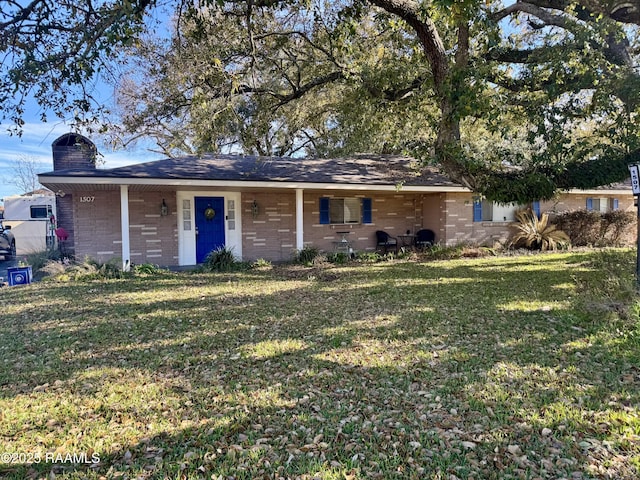 ranch-style home with brick siding, a chimney, and a front yard