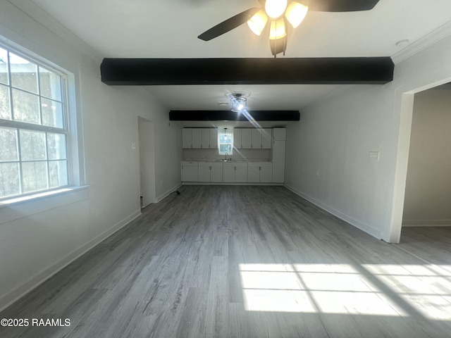 unfurnished living room with light wood-type flooring, beam ceiling, and plenty of natural light