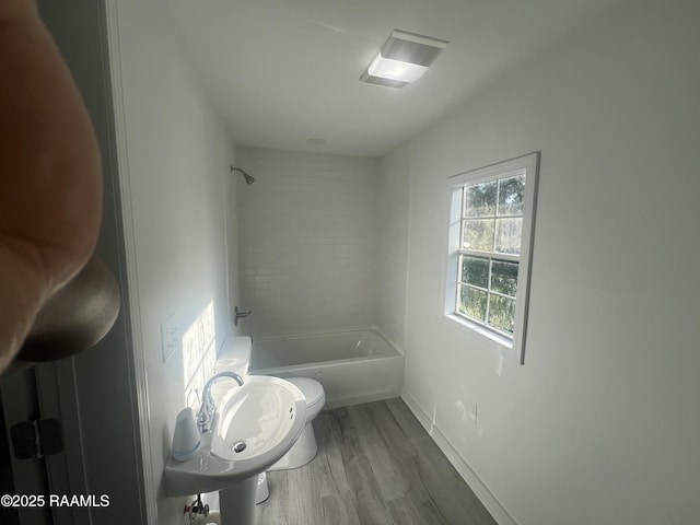 bathroom featuring shower / bath combination, baseboards, toilet, wood finished floors, and a sink