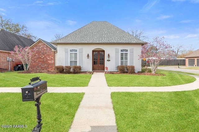 view of front facade featuring stucco siding, a shingled roof, a front lawn, and french doors