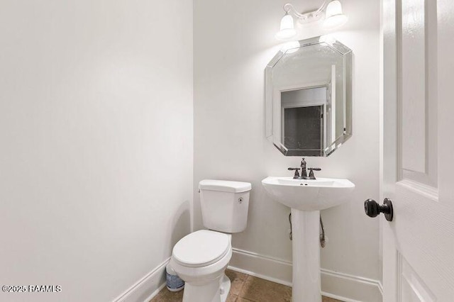 half bath featuring toilet, baseboards, and tile patterned floors