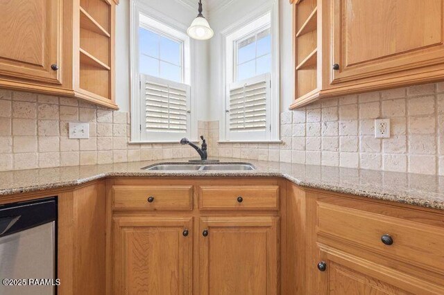 kitchen with hanging light fixtures, light stone countertops, backsplash, and a sink