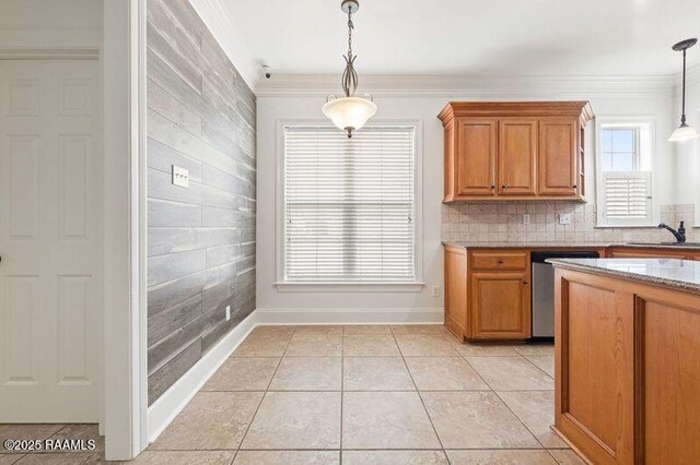 kitchen featuring brown cabinets, hanging light fixtures, ornamental molding, light tile patterned flooring, and dishwasher