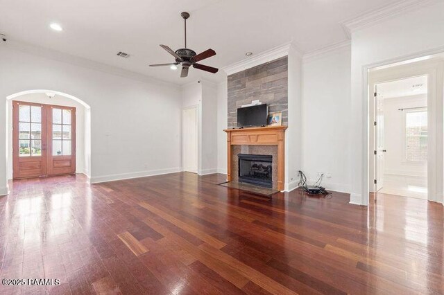 unfurnished living room with a fireplace, ornamental molding, wood finished floors, and french doors