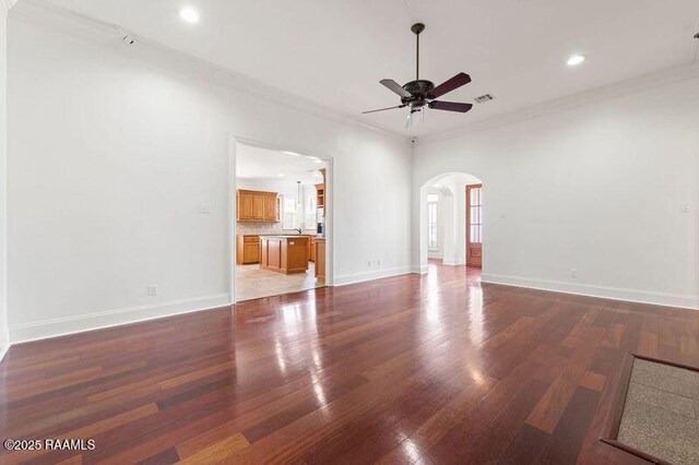 unfurnished living room featuring arched walkways, crown molding, light wood-style flooring, ceiling fan, and baseboards