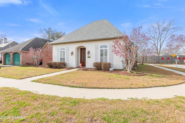 bungalow featuring roof with shingles, fence, a front lawn, and stucco siding