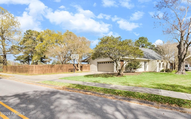 view of front of property with stucco siding, driveway, fence, a front yard, and a garage