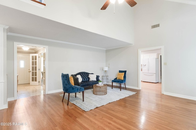 living area with visible vents, crown molding, baseboards, and wood finished floors