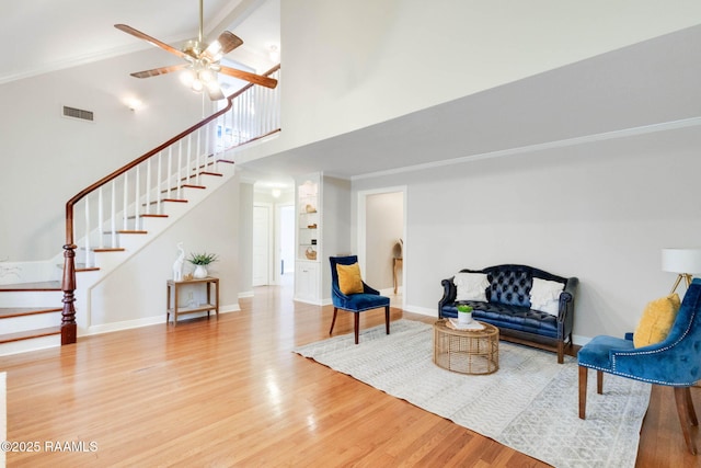 sitting room with visible vents, high vaulted ceiling, wood finished floors, stairway, and baseboards