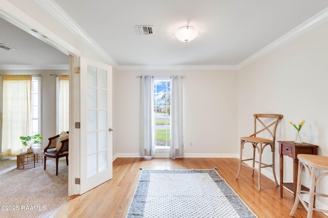 living area featuring light wood finished floors, visible vents, french doors, and ornamental molding