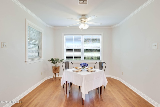 dining area with baseboards, visible vents, light wood-style flooring, ceiling fan, and crown molding