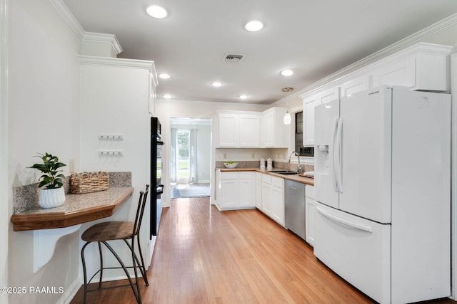 kitchen featuring visible vents, light wood-style flooring, stainless steel dishwasher, white fridge with ice dispenser, and a sink