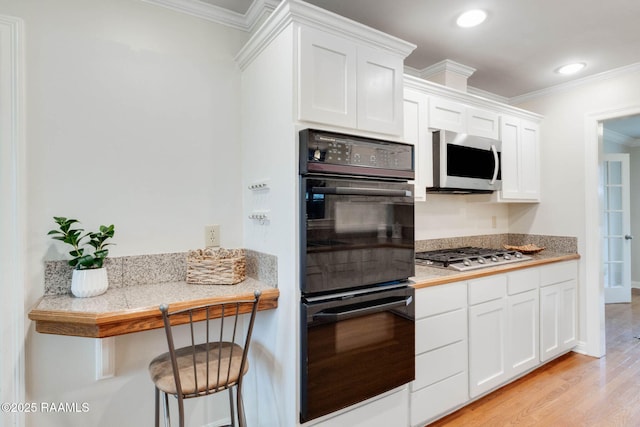 kitchen with stainless steel gas cooktop, ornamental molding, light wood-style flooring, white cabinets, and dobule oven black