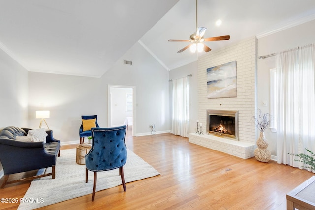 living area with visible vents, ornamental molding, a fireplace, and wood finished floors