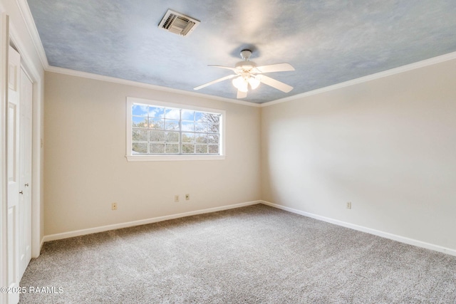 carpeted empty room featuring baseboards, a ceiling fan, visible vents, and ornamental molding