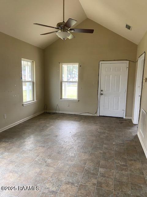 spare room with vaulted ceiling, plenty of natural light, visible vents, and baseboards